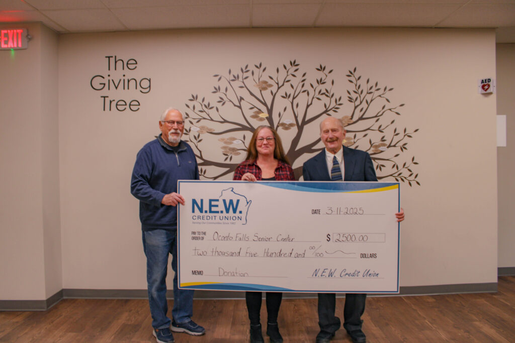 credit union board member giving large novelty check to owners of the oconto falls senior center