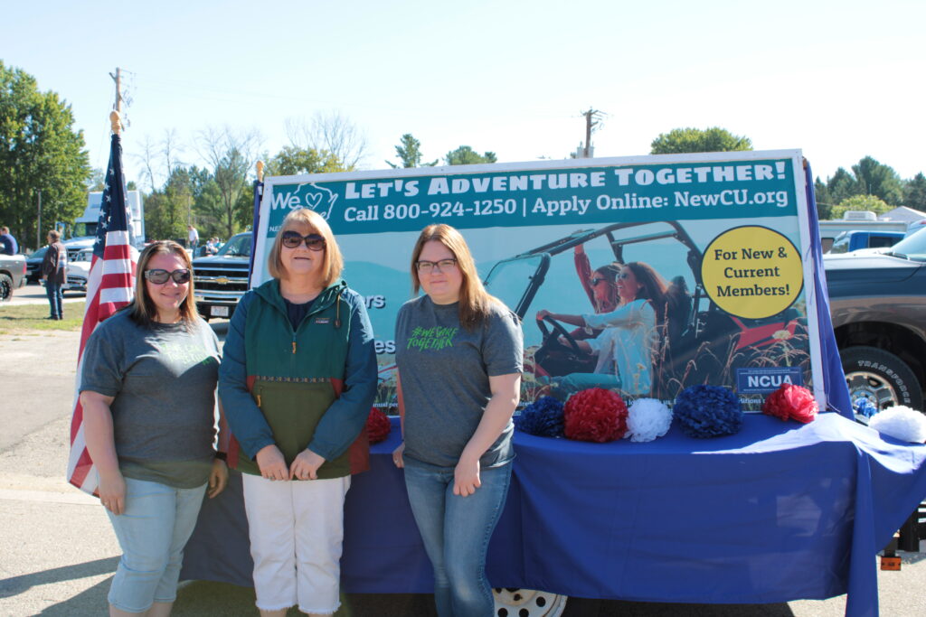 group of women standing in front of a parade float in the summer
