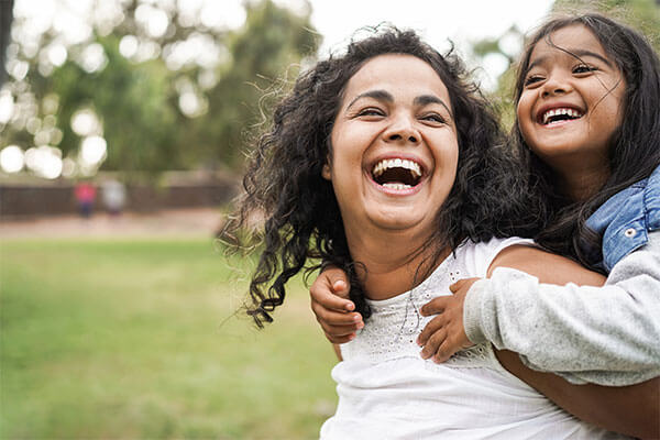 Mother holding daughter on back with big smiles