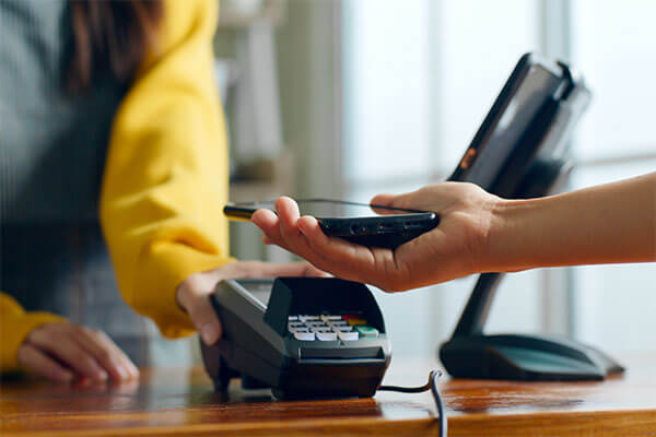 Person holding cell phone over card reader to pay.